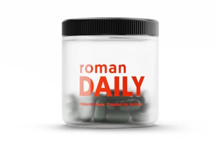 A clear bottle of Roman Daily multivitamin for men filled with dark green multivitamin capsules against a white background.